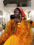Woman in an orange outfit with a red headscarf in a modern interior setting