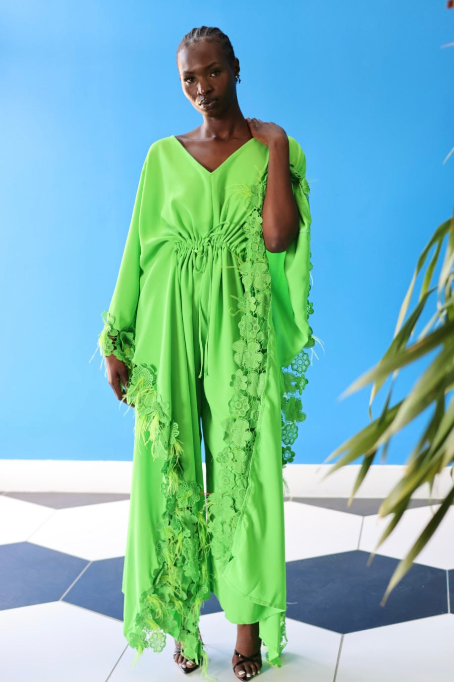 The Poppy Floral Jumpsuit in Green has gorgeous floral lace at the edge of the fabric, along with faux feathers that create a fun texture.